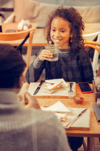 Donker-eyed dochter sandwich en drinkwater eten voor de lunch — Stockfoto