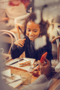 Sandviç yeme ve Smartphone cep telefonu ile video izlerken neşeli kız