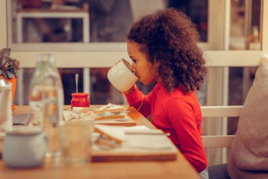 Güzel kıvırcık kız lezzetli sandviç yedikten sonra çay içme