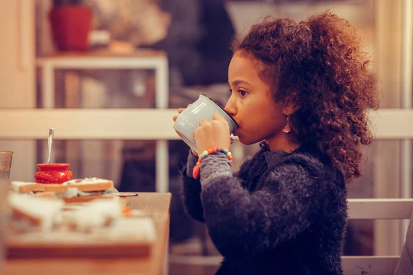 Kudrnaté tmavé vlasy dívka drží modrý hrnek při pití čaje — Stock fotografie