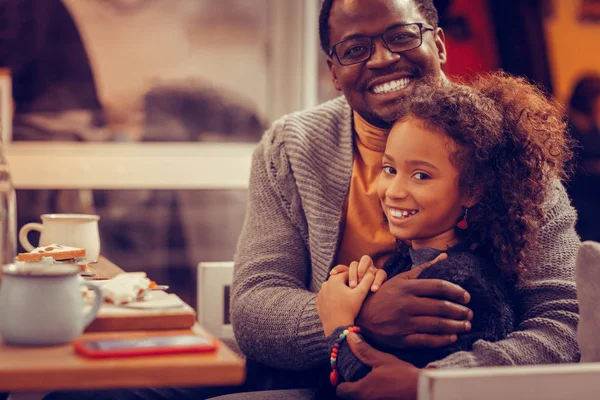 Cheerful beaming man wearing glasses feeling amazing hugging daughter — Stock Photo, Image