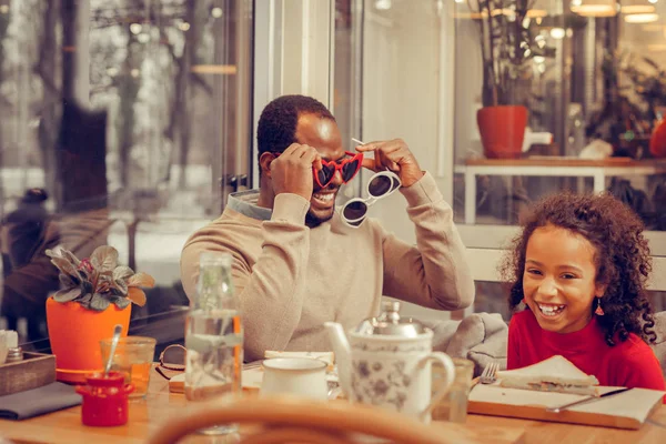 Daughter laughing while seeing her father wearing funny glasses — Stock Photo, Image