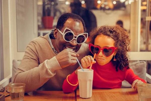 Little cute girl sharing her milkshake with her loving father — Stock Photo, Image