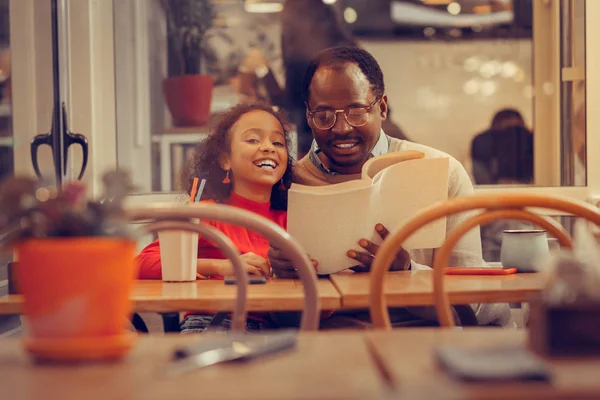 Father and daughter feeling involved in reading book together — Stock Photo, Image