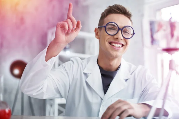 Smiling student wearing blue glasses and white coat making chemistry experiment — Stock Photo, Image