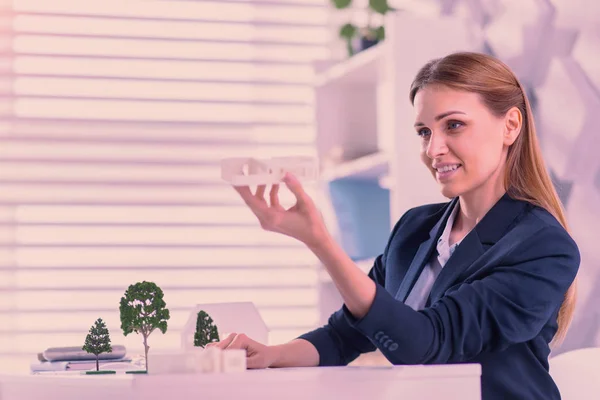 Attractive female architect elevating models at office — Stock Photo, Image