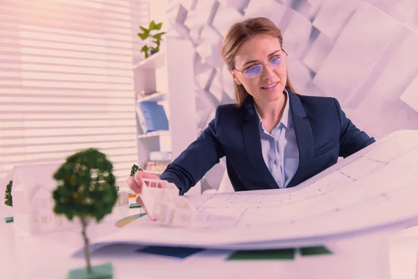 Glad female architect altering blueprint at office — Stock Photo, Image