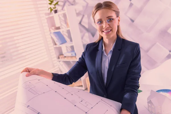 Vigorous female architect revising blueprint at office — Stock Photo, Image