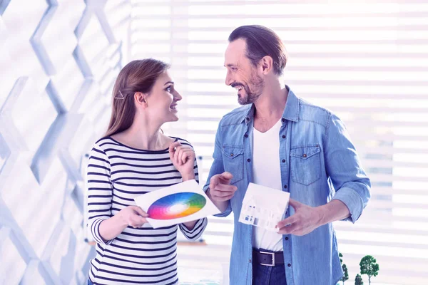 Happy people looking at each other while choosing colors for the house — Stock Photo, Image