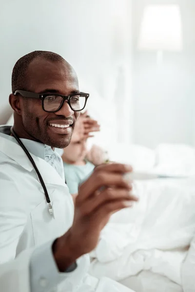 Médico internacional alegre examinando seu pequeno paciente — Fotografia de Stock