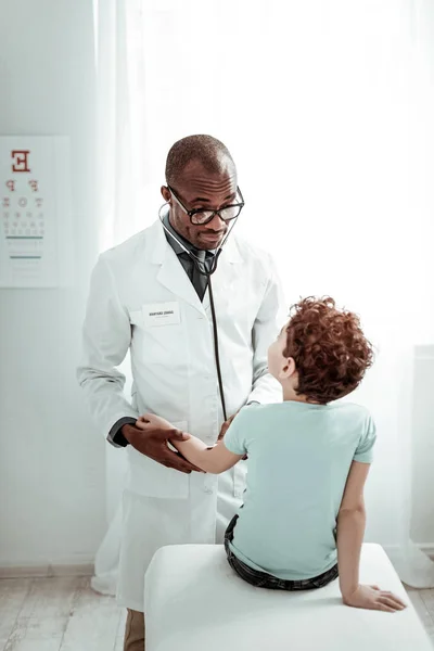 Médico internacional atento que examina a su joven visitante — Foto de Stock