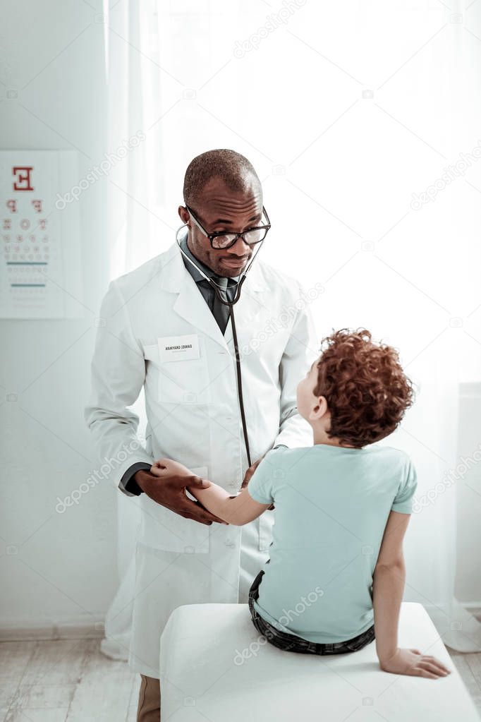 Attentive international practitioner examining his young visitor