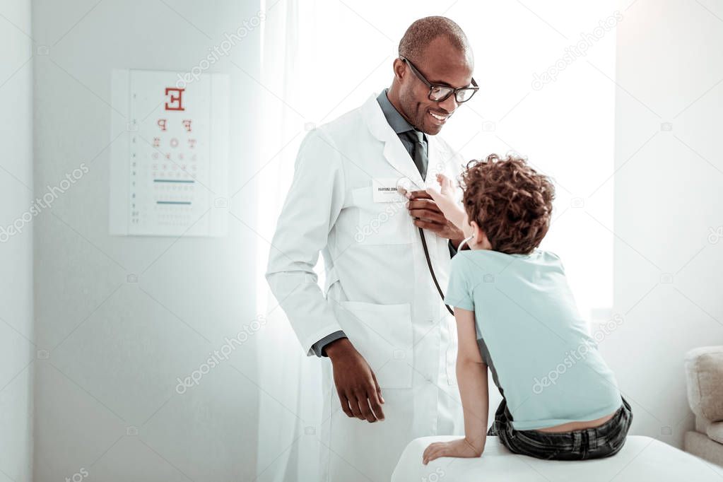 Joyful medical worker playing with little patient