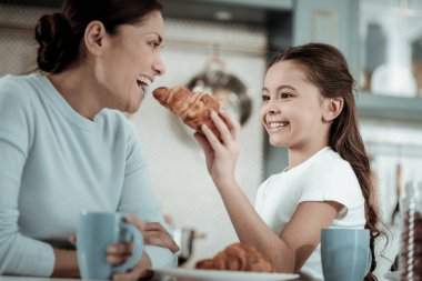 Küçük çocuk annesi bir kruvasan ile besleme