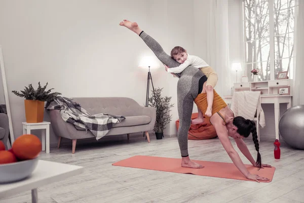 Woman doing yoga at home with her daughter