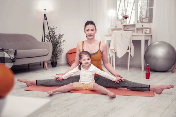 Mujer enseñando a su hija pequeña yoga y ejercicios de estiramiento —  Fotos de Stock