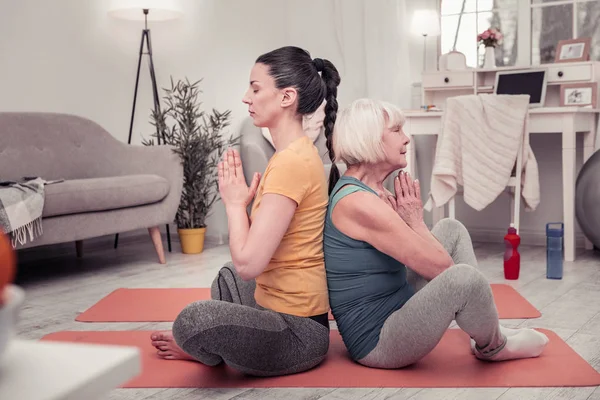 Mujer joven y una mujer de mediana edad haciendo yoga juntos —  Fotos de Stock