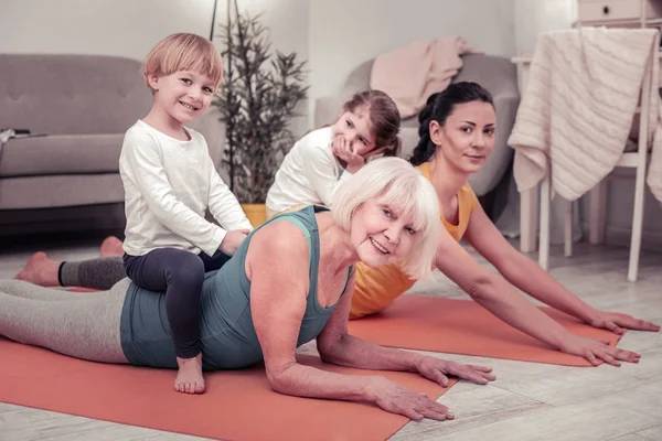 Mulheres que envolvem crianças em fazer exercícios de alongamento — Fotografia de Stock