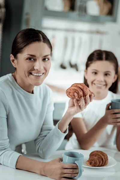 Linda senhora comendo croissants com sua filha — Fotografia de Stock