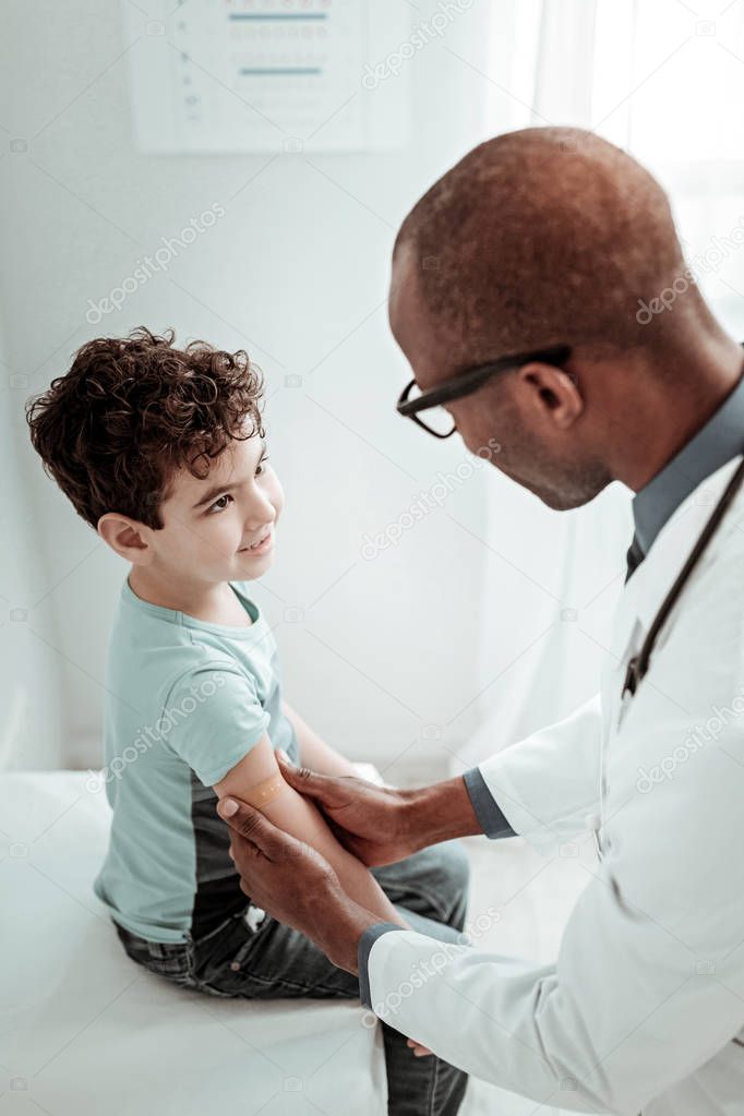 Kind brunette boy looking at his doctor