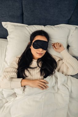 Asyalı kadın yatakta yatan siyah uyku maskesi