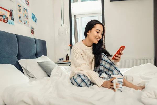 Famoso freelancer sosteniendo su teléfono inteligente mientras ve fotos — Foto de Stock