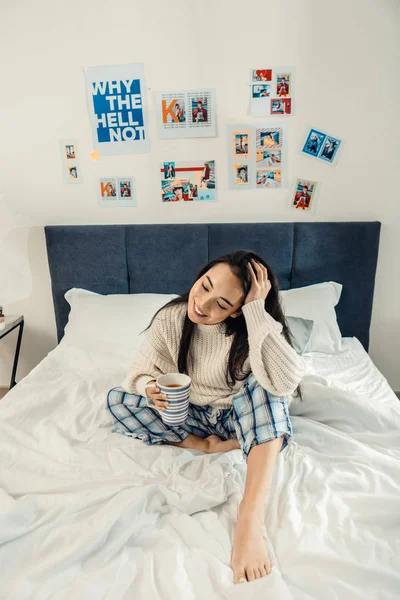 Mujer con pantalones de pijama azul bebiendo té de la mañana — Foto de Stock