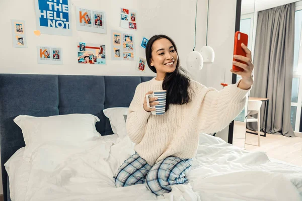 Asiática de ojos oscuros mujer haciendo selfie con taza de té de la mañana — Foto de Stock
