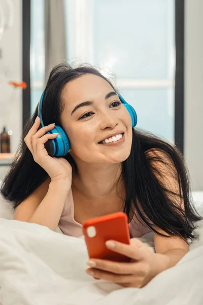 Mujer asiática relajándose en casa escuchando música en auriculares —  Fotos de Stock