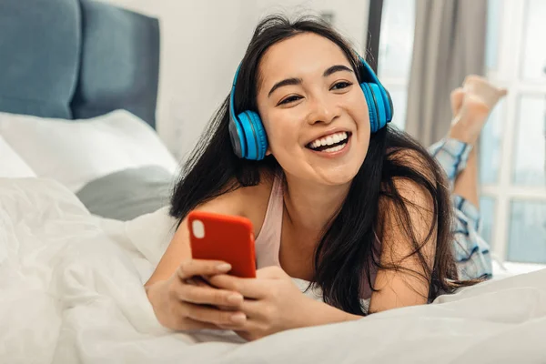 Hermosa mujer con pijama acostada en la cama y escuchando música —  Fotos de Stock