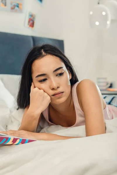 Mujer de ojos oscuros sintiéndose triste y sola acostada en su dormitorio — Foto de Stock