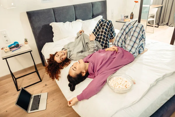 Dos novias con pijamas acostadas en la cama después de la noche de cine — Foto de Stock
