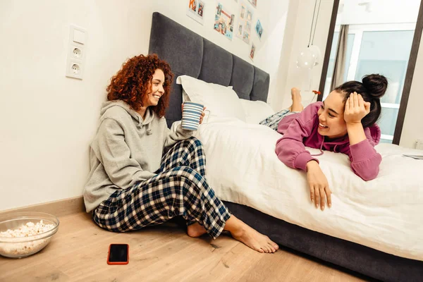 Una amiga pelirroja rizada sentada en el suelo hablando con su amiga — Foto de Stock