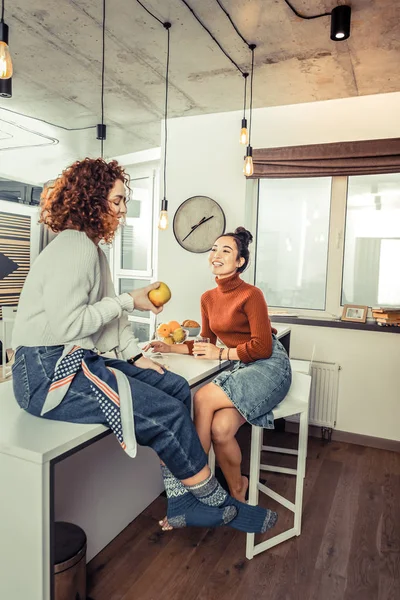 Curly red-haired roommate wearing jeans sitting on the table