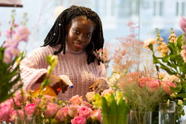 Gentile giovane designer che annaffia fiori in boutique — Foto Stock