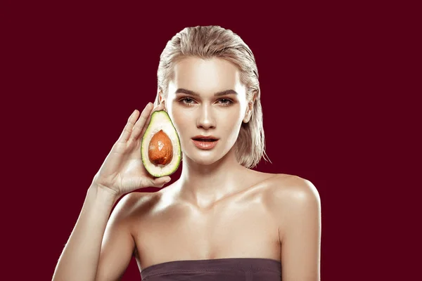 Mladá blonďatá foto model drží polovinu na pěkné avokádo — Stock fotografie