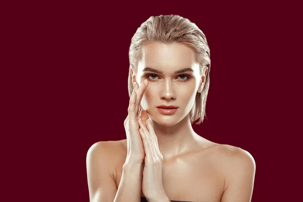 Blonda modellen med händerna nära ansiktet medan poserar — Stockfoto
