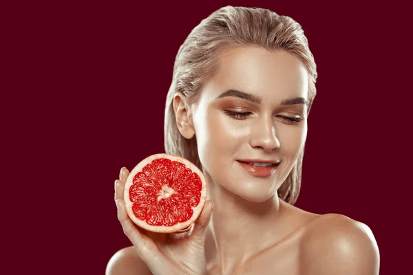 Close up of young beaming model posing with grapefruit