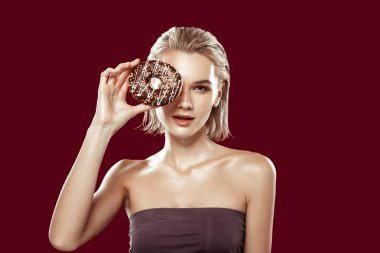 İnce genç model onun eye yakınındaki çikolatalı halka tutarak poz