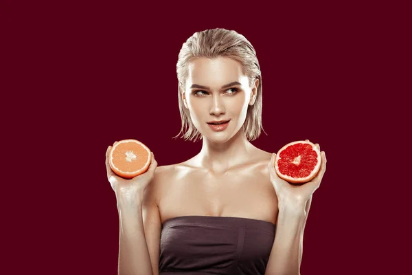 Blonde-haired model hesitating between orange and grapefruit — Stock Photo, Image