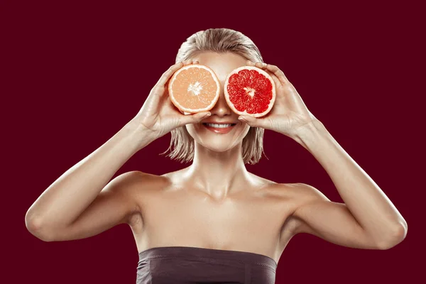 Wesoły kobieta stwarzających z pomarańczy i grejpfruta, w pobliżu jej oczy — Zdjęcie stockowe