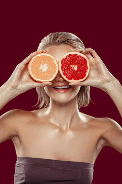 Model with short bob cut posing with orange and grapefruit