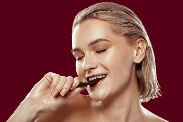 Primer plano de la mujer con maquillaje natural morder chocolate — Foto de Stock