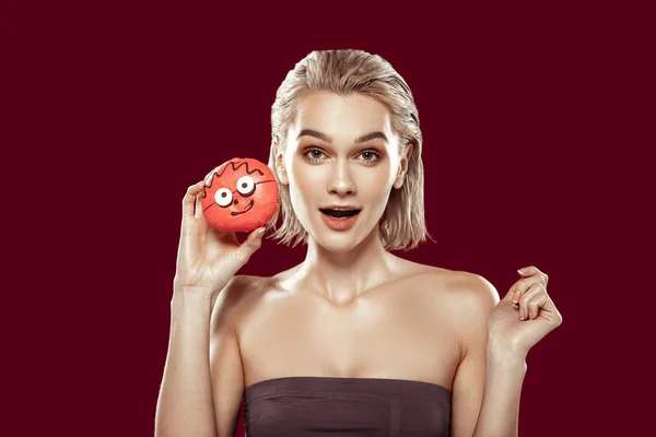 Femme blonde tenant un beignet avec un visage drôle — Photo
