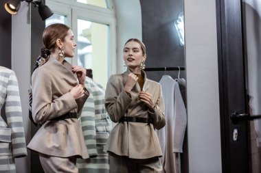 Kızıl saçlı genç gülümseyen kadın ile yeni bir takım elbise üzerinde çalışıyorum parlak makyaj