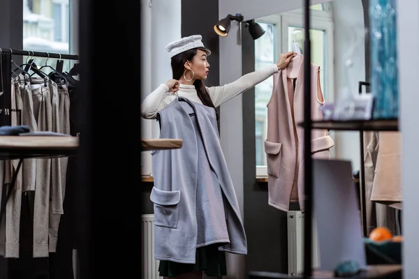 Молодая темноволосая азиатка в модном головном уборе выглядит серьезной — стоковое фото