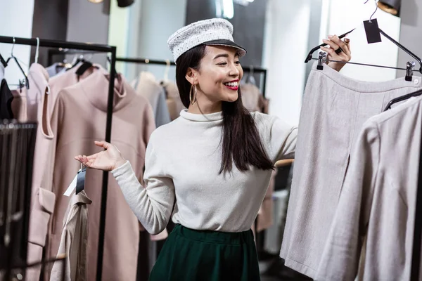 Брюнетка азиатская красивая женщина в красивой головной убор выбирая юбку — стоковое фото