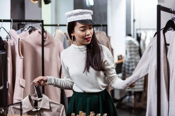 Brunette Aziatische mooie vrouw in een mooi hoofddeksel voor het kiezen van een nieuwe jas — Stockfoto