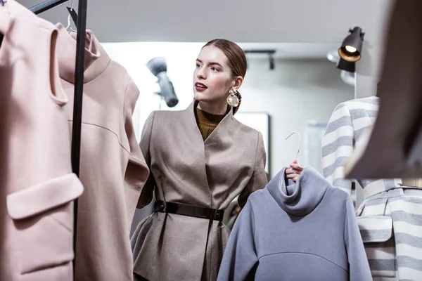 Stijlvolle langharige jonge lachende vrouw met grote oorbellen tijd doorbrengen in een showroom — Stockfoto