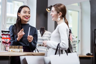 Yeni bir parfüm test bir beyaz kazaklı gülümseyen güzel uzun saçlı kadın